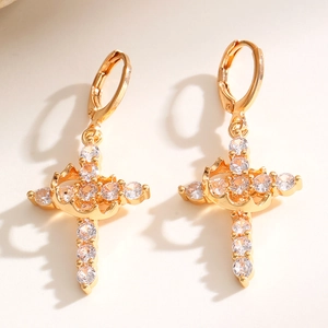 Detailed view of gold cross and crown earrings encrusted with sparkling white zircons