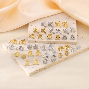 Macro shot of assorted stainless steel stud earrings with cross and ginkgo leaf designs