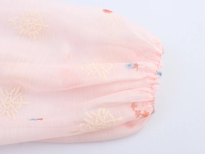 Gedetailleerde macro-opname van roze chiffon manchetten met witte bloemenborduring