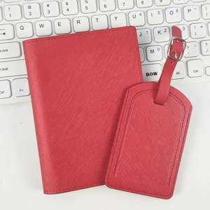 Red cross-grain PU leather passport holder and luggage tag set on keyboard