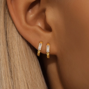 Macro shot of S925 sterling silver gold earrings with rectangular zircon on double piercings