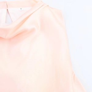 Detalle de vestido midi de satén rosa que muestra el escote drapeado y el tejido suave