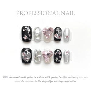 Macro shot of handmade press-on nails with silver glitter and pink heart gemstone details
