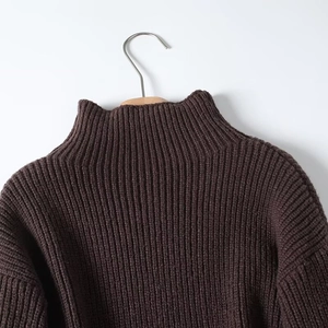 Detail of dark brown turtleneck sweater featuring thick rib knit texture and drop shoulders