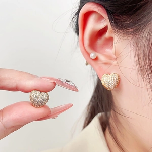 Close-up of golden heart earrings with micro-pave cubic zirconia on a model's ear