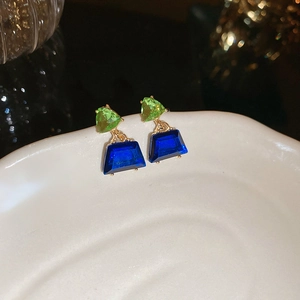 Elegant floral drop earrings with blue and green crystals on a ceramic display