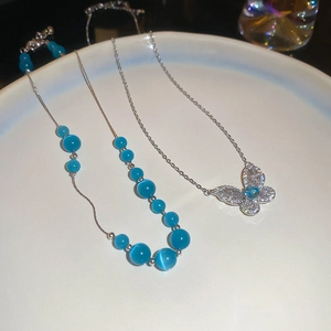 Detailed shot of silver butterfly pendant with blue opal beads and zircon inlay in a ceramic tray