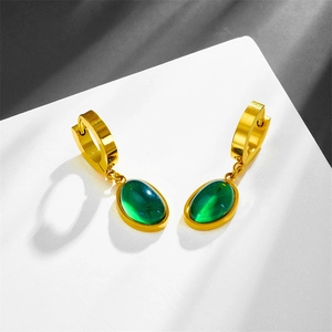 Detailed view of elegant gold-toned earrings with green oval gemstones on white background