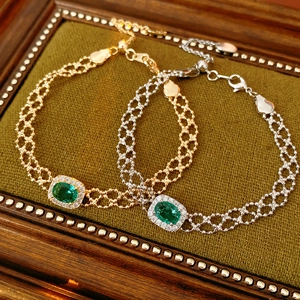 Macro detail of vintage gold and silver bracelets with green gemstones on green velvet