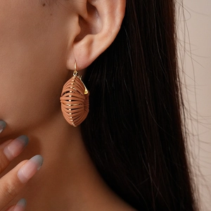 Detail of woven brown leather hoops on a model showcasing vintage minimalist aesthetic