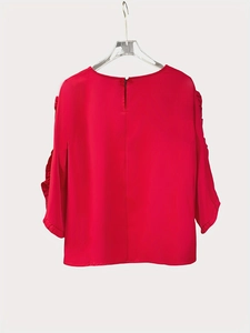 Detail of red chiffon blouse with ruffled cuffs and back button closure on a hanger