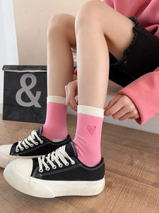 Detail shot of pink crew socks with white ribbed cuffs and love heart embroidery