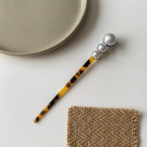 Detail of amber-patterned hair pin with three gradient pearls in minimalist style