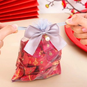Detailed view of gray organza gift bag with satin bow and pearl accent for weddings