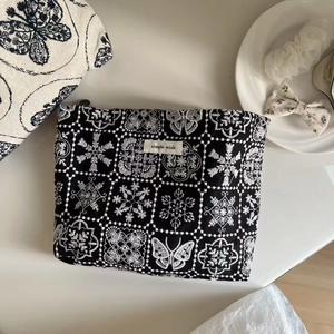 Detailed embroidery of white butterflies and floral patterns on black canvas bag