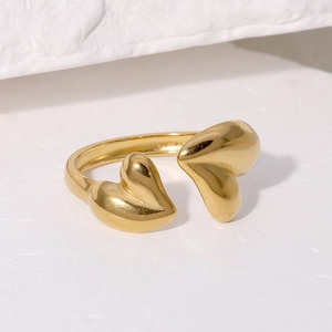 Minimalist gold heart-shaped open ring with asymmetric crossover design on stone background