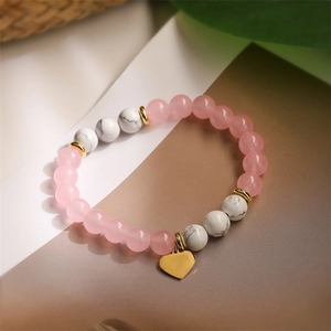 Close-up of pink agate and marble beads with a gold heart pendant and metal spacers