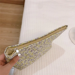 Detail shot of a floral canvas cosmetic bag with purple patterns and a metal zipper