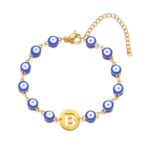 Detailed close-up of golden evil eye bracelet with blue beads and hollow letter B charm