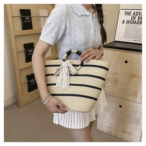 Close-up of woven tote bag with black stripes and elegant white lace bow detail