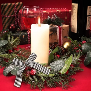 Christmas candle wreath with green pine, red berries and a black-white checkered bow