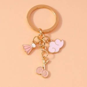 Macro detail of pink enamel badminton racket and cloud charms on golden keychain