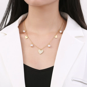 Detail of gold heart pendant necklace with tiny diamonds and pearls on a model