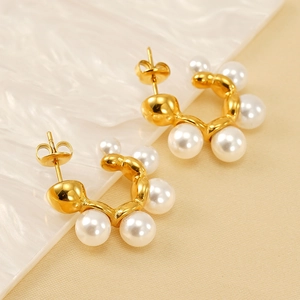 Elegant gold-plated C-shaped hoop earrings with inlaid white pearls on a textured background