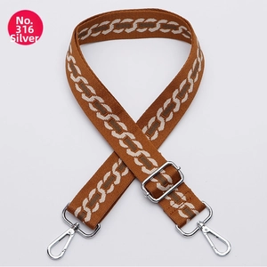 Detail of adjustable woven bag strap with brown geometric jacquard and silver hardware