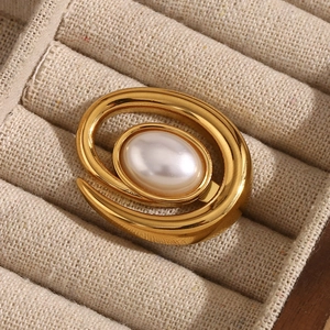 Detailed macro view of 18K gold plated conch shell pearl brooch on beige linen