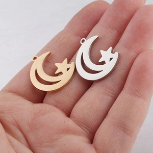 Detailed view of gold and silver hollow moon star pendants displayed on a palm