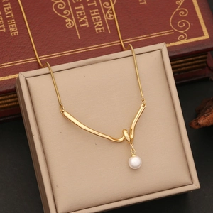 Macro shot of gold double layer necklace with twisted bar pendant and white pearl