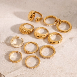 Detailed flat lay of eleven golden stainless steel rings with zircon on marble