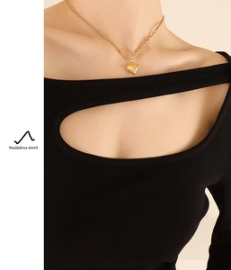 Detail of a 3D heart pendant necklace with unique mixed chain design in gold stainless steel