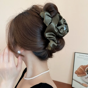 Detailed view of an olive green pleated satin cloud hair clip with a silky texture