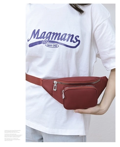 Detail of burgundy waterproof nylon waist bag with silver zippers worn by a model