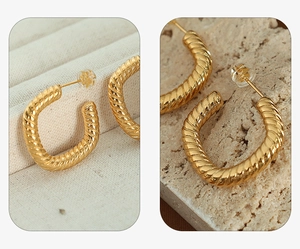 Detail of gold U-shaped hoop earrings with twisted spiral texture and metallic luster