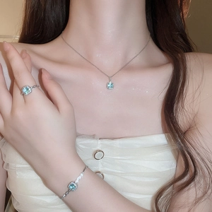 Close-up of aquamarine jewelry set featuring square pendants on model in white outfit