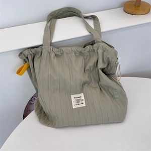 Close-up of sage green pleated tote bag with drawstring closure and striped texture