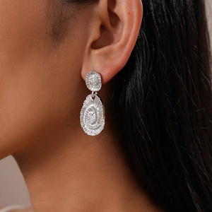 Gros plan de boucles d'oreilles ovales argentées avec spirales et petits diamants