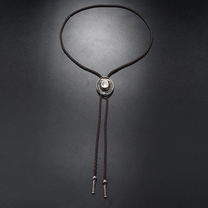 Detail of vintage silver cowboy hat slide and engraved metal tips on brown bolo tie leather
