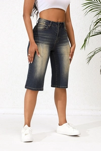Detail of high-waist dark blue vintage wash denim Bermuda shorts with classic cat-whisker texture