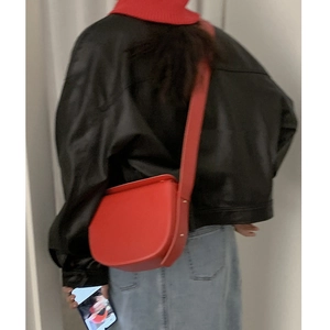 Chic red PU leather saddle bag worn by a model with a black jacket and red scarf