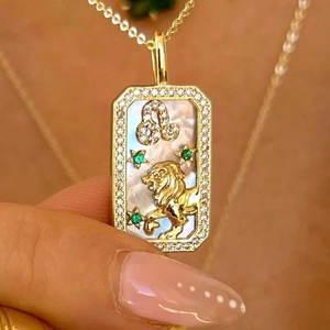 Golden Leo zodiac necklace with white shell pendant, rhinestones and green gemstone accents