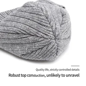 Close-up of the sturdy top closing and fine knit texture of a grey winter beanie hat