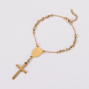Close-up of golden beaded bracelet featuring a cross pendant and religious medal
