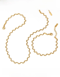 Detail of twisted gold stainless steel jewelry set featuring a necklace and bracelet