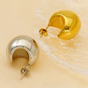 Macro view of polished gold and silver water drop earrings on silk texture
