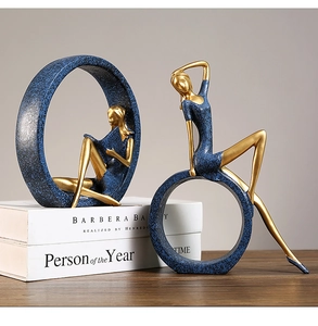 Detail of Nordic resin statues featuring a gold and blue woman reading on a shelf
