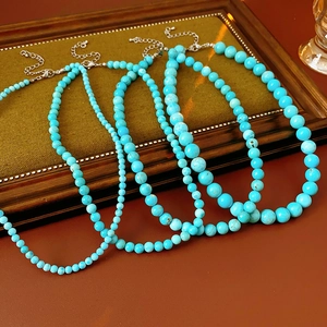 Detailed macro view of four turquoise beaded necklaces displayed on a vintage wood tray